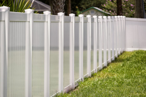 A white vinyl fence surrounding a backyard.