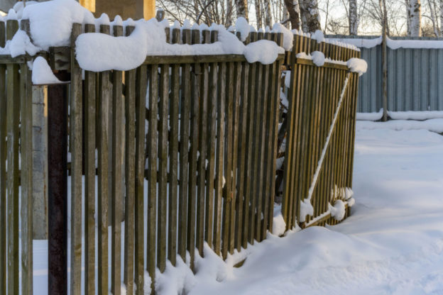 A wood fence with snow on it.