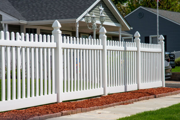 A white fence in the front yard of a home.